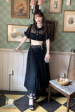 Woman in a stylish black outfit standing in a room with vintage decor.