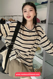 Woman wearing a striped sweater in an indoor setting with shelves in the background