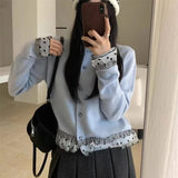 Person wearing a light blue sweater with patterned cuffs and hem, holding a phone.