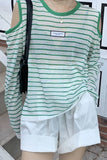 Person wearing a green and white striped shirt with a label, white shorts, and carrying a black bag.