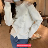 Person wearing a white sweater with button details in an indoor setting