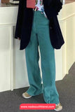 Person wearing teal corduroy pants with a black coat and colorful shirt in an indoor setting.