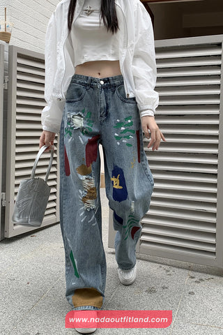 Person wearing a white jacket and colorful jeans with a blurred background